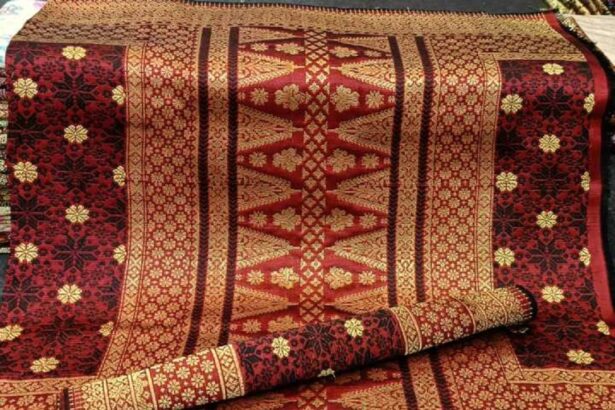 Decorative red and gold patterned rug with intricate floral motifs, partially rolled up