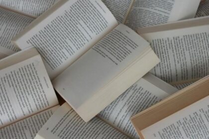 Several paperback books opened to pages, scattered in a pile and full of text.