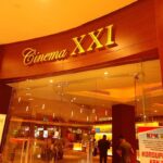 Entrance to Cinema XXI with glass doors and a warm wood facade