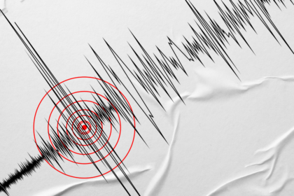 Seismograph recording with jagged black lines and red concentric circles marking a tremor focus on crumpled paper.