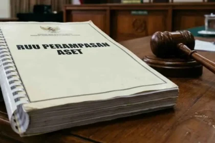 A large legal document titled 'RUU PERAMPASAN ASET' on a wooden table next to a judge's gavel in a courtroom setting.
