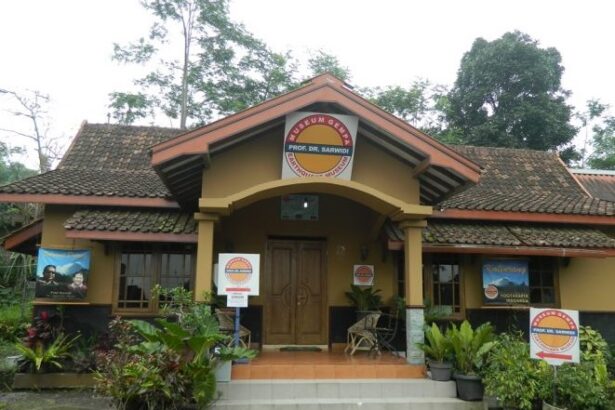 Front view of a small museum building with yellow walls, red-tiled roof, and a circular sign above the entrance.