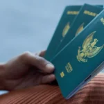 Blue Indonesian passport held in a hand, showing the crest on the cover against a blurred background