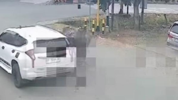 White SUV parked on a street next to a curb, with another car visible on the right; appears to be a CCTV frame with pixelated artifacts across the image.