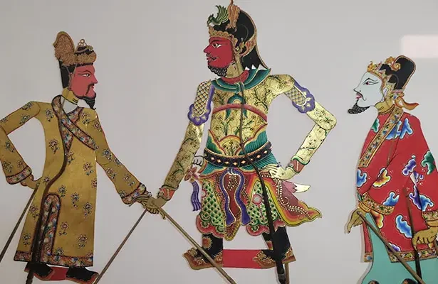Three ornate warrior figures in colorful traditional robes, standing with swords, mid-heroic scene.