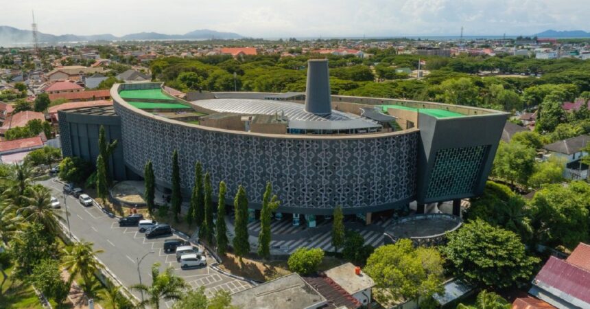 whatsapp_image_2024_12_26_at_15_14_011 - Mabur.co Aerial view of a circular modern building with lattice walls and green rooftop terraces in a tropical city.