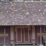 Small wooden traditional house with a decorative carved facade and a tiled roof.