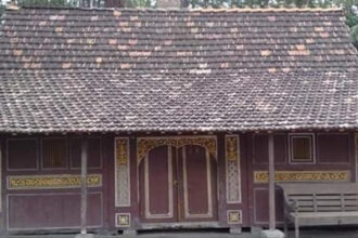 Small wooden traditional house with a decorative carved facade and a tiled roof.