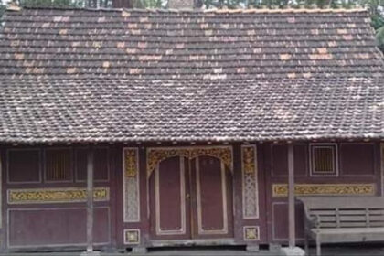 Small wooden traditional house with a decorative carved facade and a tiled roof.