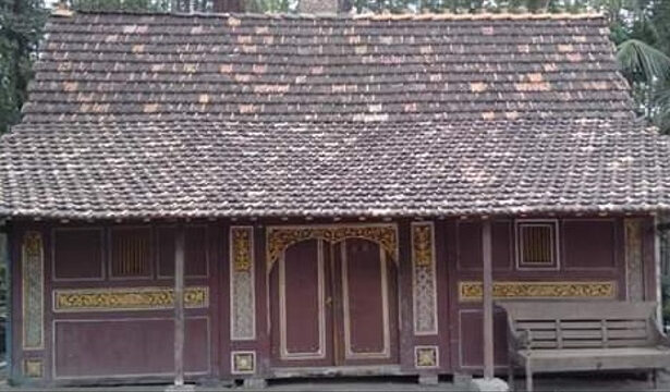Small wooden traditional house with a decorative carved facade and a tiled roof.