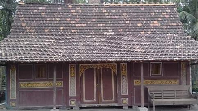 Small wooden traditional house with a decorative carved facade and a tiled roof.