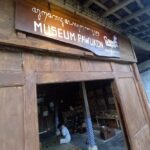 Entrance to a wooden museum with a sign 'MUSEUM PAWUKON' above the doorway