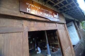 Entrance to a wooden museum with a sign 'MUSEUM PAWUKON' above the doorway