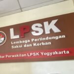 Maroon wall sign for LPSK (Lembaga Perlindungan Saksi dan Korban) with circular logo on left and large white LPSK letters across the top.
