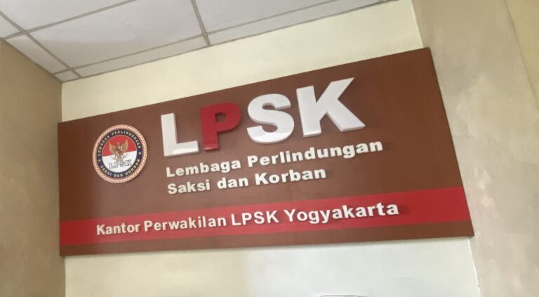 Maroon wall sign for LPSK (Lembaga Perlindungan Saksi dan Korban) with circular logo on left and large white LPSK letters across the top.