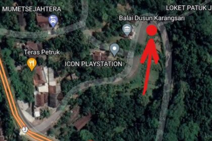 Satellite map of a forested area showing roads, with a red location pin low-left and a red arrow pointing to a spot near Balai Dusun Karangsari and ICON PLAYSTATION.