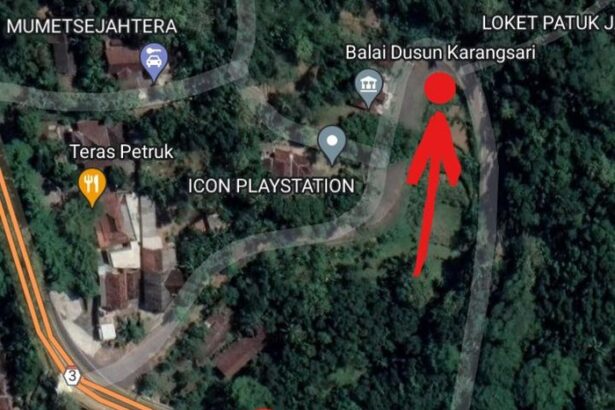 Satellite map of a forested area showing roads, with a red location pin low-left and a red arrow pointing to a spot near Balai Dusun Karangsari and ICON PLAYSTATION.
