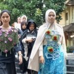 Group of women wearing hijabs and colorful traditional outfits walking down steps outdoors; a building is in view behind them.
