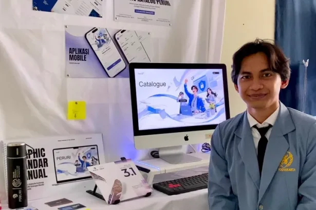Man in a blue blazer stands beside a desk with an iMac showing a 'Catalogue' screen at a booth or exhibition.",